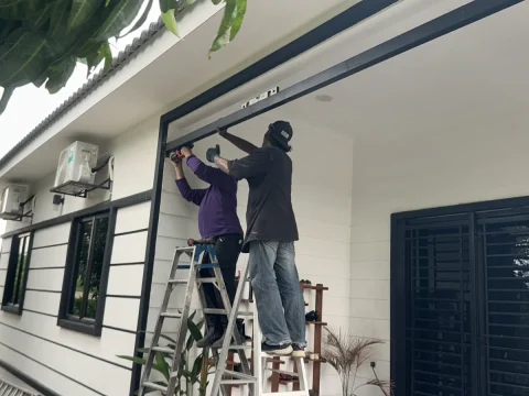 Pekerja memasang struktur di bahagian hadapan rumah